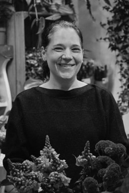 Laura, the florist behind Betty June Flowers, smiling in her Wood Street studio surrounded by seasonal flowers