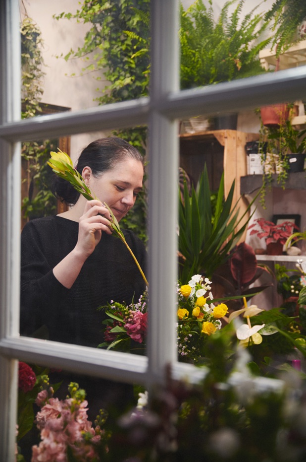 Laura of Betty June Flowers arranging wild, seasonal flowers at a Georgian sash window in her Wood Street studio